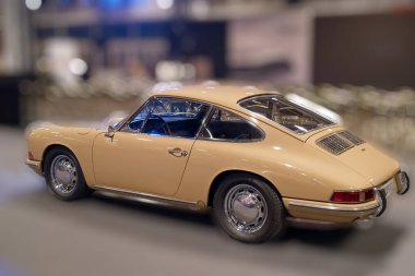 Klasik bir araba kapalı bir sergi alanında sergilenir. İnsanlar etkinliğin etrafında toplandı, araca hayran kaldılar. Sahne, arabanın ve kalabalığın detaylarını yakalıyor..