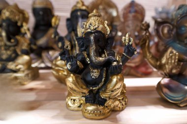 Ganesha 'nın küçük figürleri ahşap bir yüzeye yerleştirilmiştir. Heykeller farklı renkler ve tasarımlar gösteriyor. Müşteriler mağazada ruhani hediyeler arayabilirler..