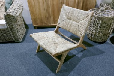 Bir ev dekoratöründe dokunmuş koltuğu ve ahşap bacakları olan bir sandalye gösterilir. Tasarım basit zanaatı ön plana çıkarıyor. Mağazada çeşitli sepetler ve mobilyalar var..