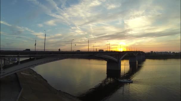 Zeilboot zeilen onder de brug bij zonsondergang — Stockvideo