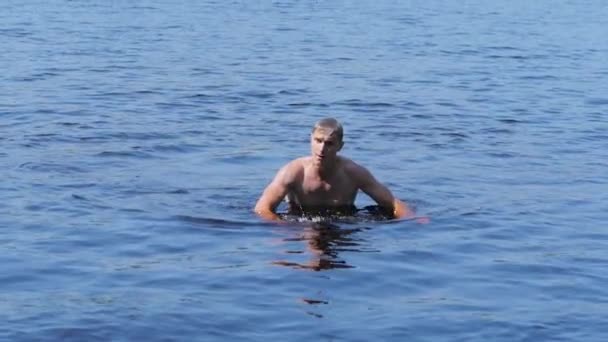Молодой человек купается в реке — стоковое видео