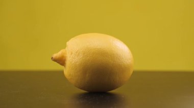 Buz küpleri limonun üzerine düşer. Ağır çekim. Sarı arka plan. Makro mod. Tazelik