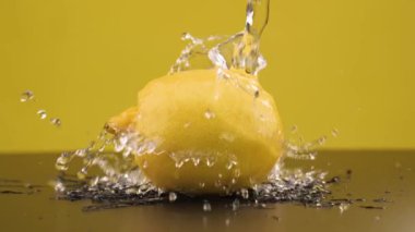 Buz küpleri limonun üzerine düşer. Ağır çekim. Sarı arka plan. Makro mod. Tazelik