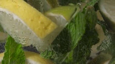 Su damlaları, kireç ve nane parçaları, siyah bir arka planda, yakın plan