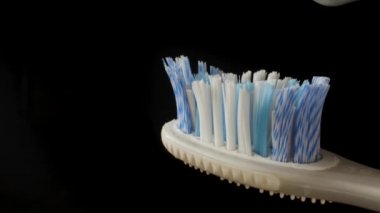 Diş fırçasına diş macunu sürüyorum. Makro plan. Siyah anahtar. Siyah arkaplan