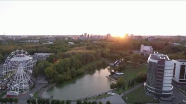 Şehir parkında büyük beyaz bir dönme dolap. Şehir trafiği.