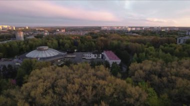 Şehir parkında büyük beyaz bir dönme dolap. Şehir trafiği.