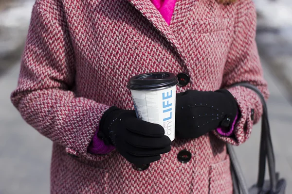 Hermosa mujer joven caminar al aire libre en el parque con una taza de café de plástico, que ella toma en sus manos — Foto de Stock