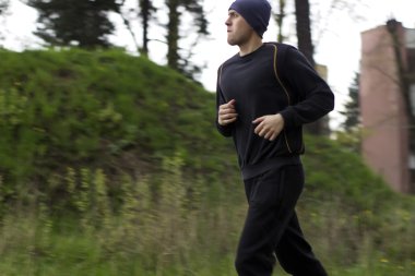 Yumuşak ve anlayışı bulanıklık. Genç adam yakın kadar spor giyim bir sokakta bulutlu hava çalışıyor devreye girer