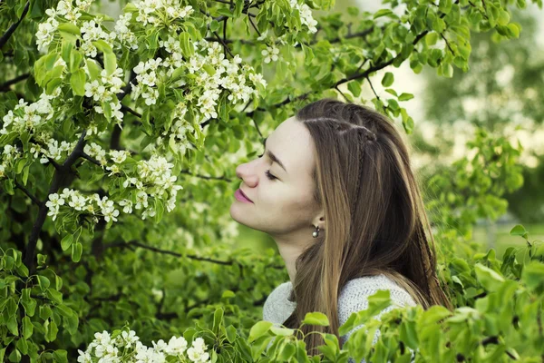 Ritratto di bella ragazza ravvicinata tra un albero in fiore con foglie verdi all'aperto — Foto Stock