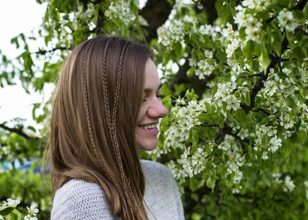 Портрет красивой молодой девушки рядом с цветущим деревом с зелеными листьями на открытом воздухе — стоковое фото