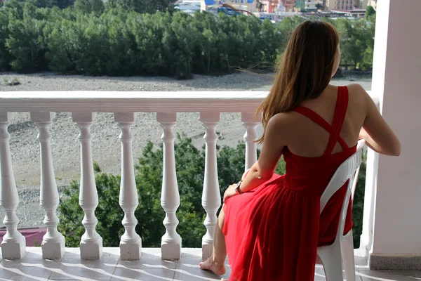 Bella ragazza seduta sulla sedia bianca all'aperto sul balcone e guardare sul bellissimo paesaggio — Foto Stock