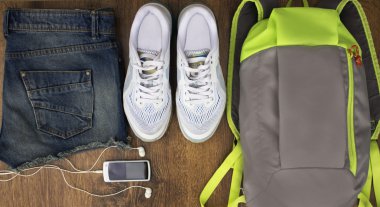 Spor ayakkabı için ayarla, sırt çantası, kot şort yakın çekim bir ahşap arka plan, üstten görünüm