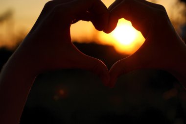 Kadın el hangi aracılığıyla güneş ışınları günbatımında yapmak kalp şeklinde geçti