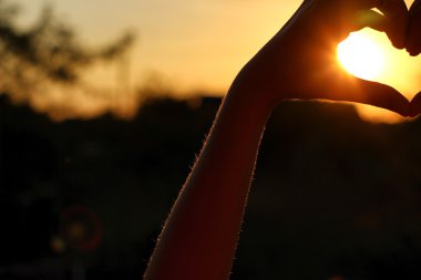 Kadın el hangi aracılığıyla güneş ışınları günbatımında yapmak kalp şeklinde geçti