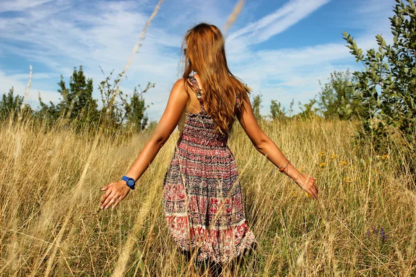 Giovane bella ragazza che cammina nel campo e corre mano attraverso l'alta erba secca in estate — Foto Stock