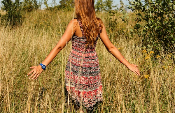 Giovane bella ragazza che cammina nel campo e corre mano attraverso l'alta erba secca in estate — Foto Stock