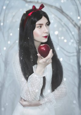 Beyaz tenli ve kırmızı dudaklı genç bir kadın kırmızı zehirli elmayı saklıyor. Şimdi beyaz prenses kostümü. Sanat fotoğrafı..