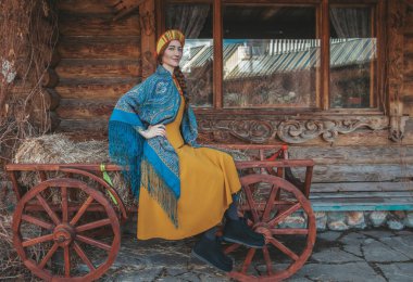 Geleneksel elbiseli Rus güzeli saman arabasında oturuyor..