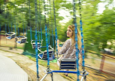 Zincirleri üzerinde askıya bir salıncak üzerinde genç güzel kız rides