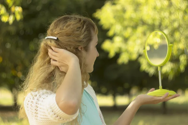 Jovem menina bonita olhar para o espelho no parque.Concepção suave e borrão — Fotografia de Stock
