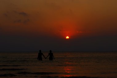 Güzel kızlar denizde günbatımında elele silüeti