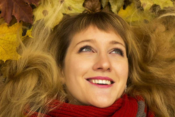 Young beautiful girl lying on autumn leaves and smiling — Stock Photo, Image