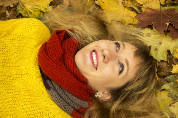 Young beautiful girl lying on autumn leaves and smiling — Stock Photo, Image