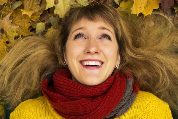 Young beautiful girl lying on autumn leaves and smiling — Stock Photo, Image