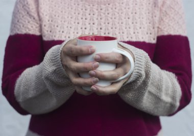 Bir kadın ve bir fincan sıcak çay tutan elleri ısıtır
