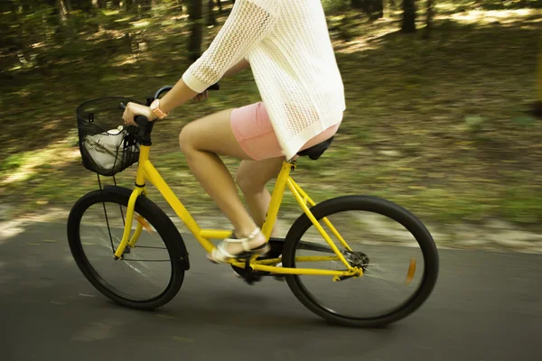 Rozmycie ruchu. Jazda żółty rower na drogach leśnych. Zbliżenie: młoda kobieta jazdy rowerem — Zdjęcie stockowe