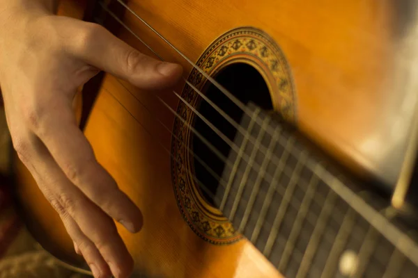 Mladý člověk hraje na kytaru. Detail ruky a kytara. Měkký a rozostření početí — Stock fotografie