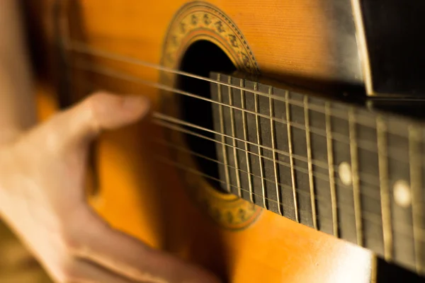Mladý člověk hraje na kytaru. Detail ruky a kytara. Měkký a rozostření početí — Stock fotografie
