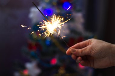 Yumuşak ve anlayışı bulanıklık. Yanan bir maytap closeup tutan el. Yeni yıl ve Noel