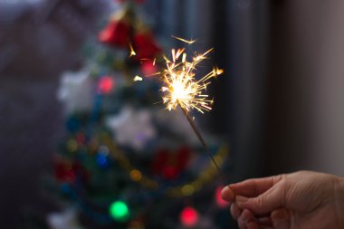 Yumuşak ve anlayışı bulanıklık. Yanan bir maytap closeup tutan el. Yeni yıl ve Noel