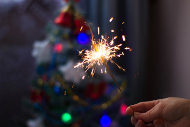 Yumuşak ve anlayışı bulanıklık. Yanan bir maytap closeup tutan el. Yeni yıl ve Noel