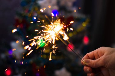 Yumuşak ve anlayışı bulanıklık. Yanan bir maytap closeup tutan el. Yeni yıl ve Noel