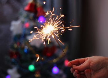 Yumuşak ve anlayışı bulanıklık. Yanan bir maytap closeup tutan el. Yeni yıl ve Noel