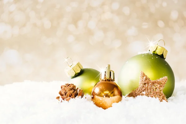 Grüne und goldene Weihnachtskugeln auf Schnee — Stockfoto