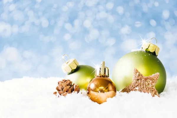 Grüne und goldene Weihnachtskugeln auf Schnee — Stockfoto