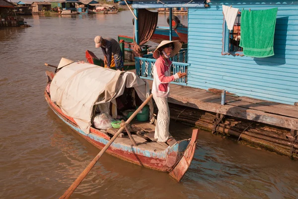 Vietnamita chica en un sombrero de paja con grandes márgenes está de pie con un enorme barco de remos — Foto de Stock