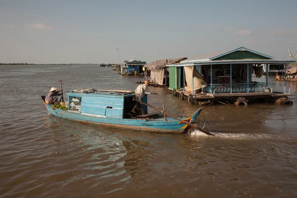 Chico dirige el barco, que sale de las calles de la aldea en el lago Tonle Sap agua en Camboya . — Foto de Stock