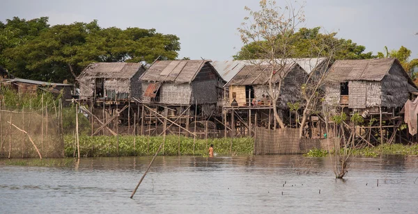 Pequeña casa en el agua, un niño pescando con un cuenco de hierro — Foto de Stock