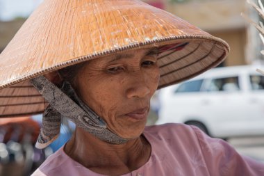 Büyükanne bir hasır şapka giyiyor. Vietnamca büyükanne kaşlarını uzak kameradan arıyorum onun yüzünde ile hasır şapkalı. Aralık 4, 2009: Büyükanne, 80 yaşında, Vietnam, Vung Tau