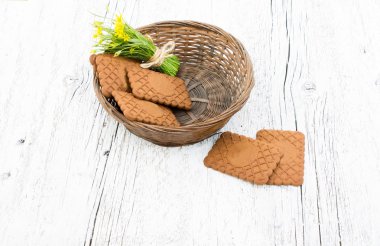 Çerezler üzerinde beyaz bir ahşap arka plan ile sepet içinde sarı çiçekler buket