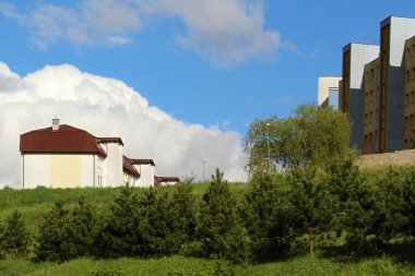 Yeşil ağaçların yanındaki beyaz ev bulutlu gökyüzüne karşı