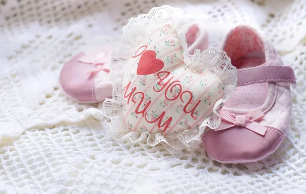 Textile handmade white heart with the inscription I love mum and little pink baby shoes on a white knitted napkin — Stock Photo, Image