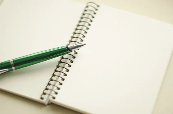 Une partie du carnet blanc vierge ouvert et stylo vert sur le bureau Photos De Stock Libres De Droits