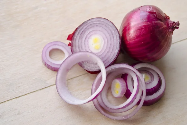 Sliced fresh red onion isolated on wooden background. Full and choppen onion. Closeup shoot