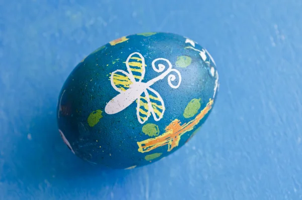 Un colorido huevo de Pascua hecho a mano aislado sobre un fondo azul — Foto de Stock
